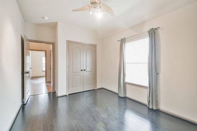 unfurnished bedroom featuring dark hardwood / wood-style floors, ceiling fan, and a closet