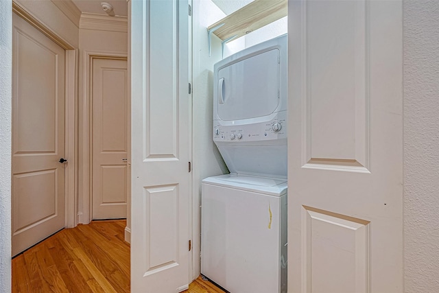 clothes washing area featuring crown molding, stacked washer / dryer, and light hardwood / wood-style flooring