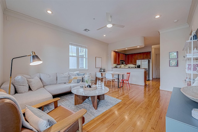 living room featuring ceiling fan, crown molding, and light hardwood / wood-style flooring