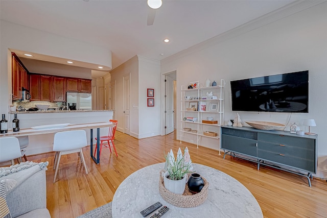 living room featuring ceiling fan, light wood-type flooring, and ornamental molding