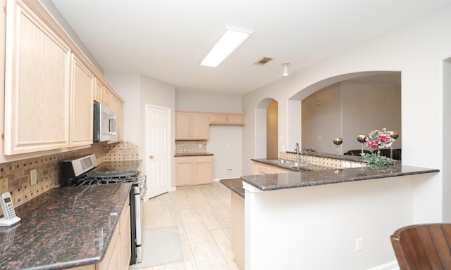 kitchen featuring dark stone countertops, tasteful backsplash, kitchen peninsula, and appliances with stainless steel finishes