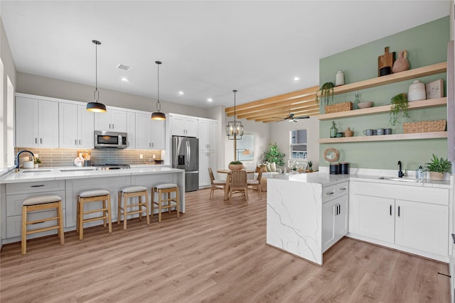 kitchen featuring kitchen peninsula, appliances with stainless steel finishes, a breakfast bar, sink, and white cabinetry