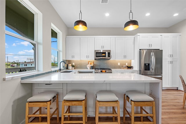 kitchen with white cabinets, stainless steel appliances, hanging light fixtures, and sink