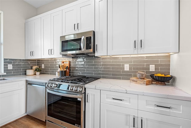 kitchen with decorative backsplash, light stone countertops, white cabinetry, and stainless steel appliances