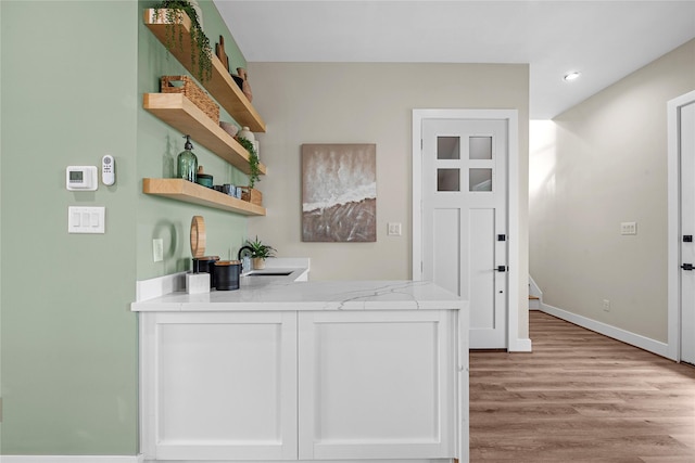 bar with sink, white cabinets, and light hardwood / wood-style flooring