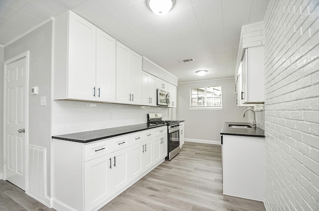 kitchen featuring white cabinets, appliances with stainless steel finishes, light hardwood / wood-style flooring, and sink