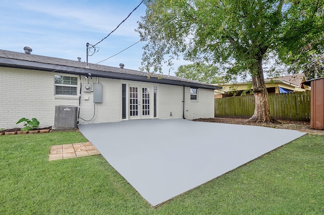 rear view of house with a lawn, a patio area, central air condition unit, and french doors