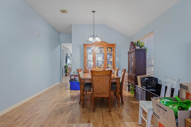 dining space featuring a chandelier, light wood-type flooring, and vaulted ceiling