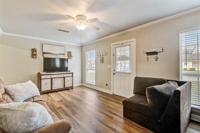 living room with ceiling fan, a wealth of natural light, wood-type flooring, and crown molding