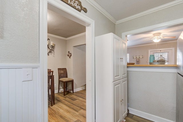 hallway with ornamental molding and light hardwood / wood-style flooring