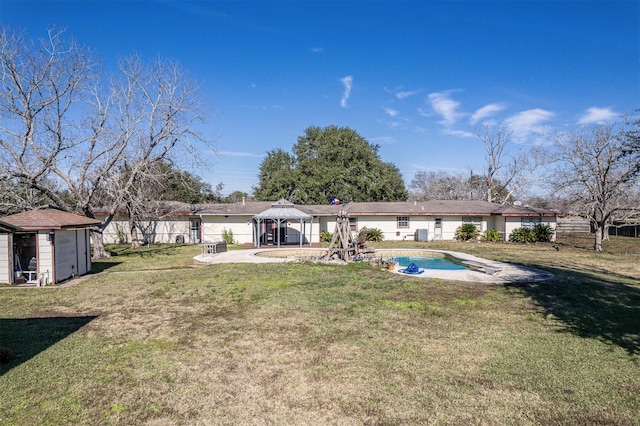 back of property with a gazebo, a yard, a fenced in pool, and a storage unit