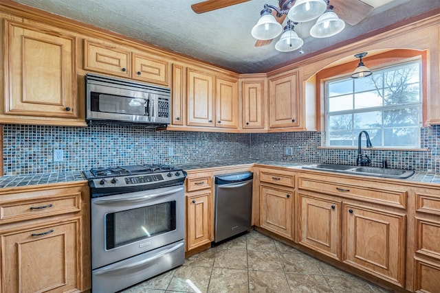 kitchen with decorative backsplash, appliances with stainless steel finishes, tile countertops, and sink