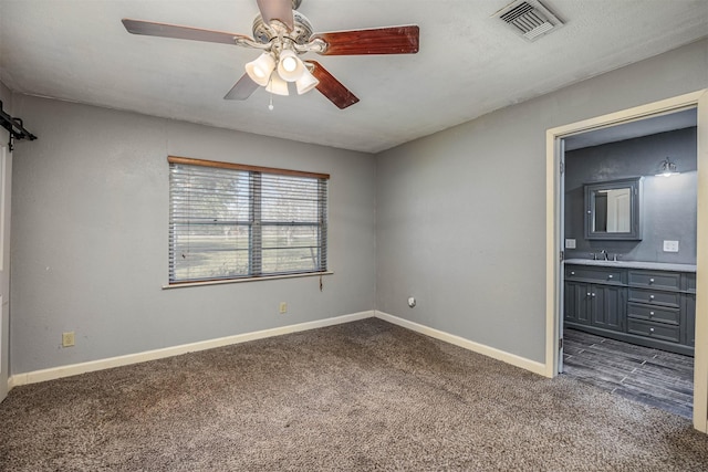 unfurnished bedroom with dark colored carpet, ceiling fan, sink, and ensuite bath