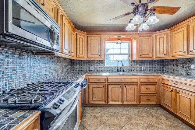 kitchen with backsplash, sink, a textured ceiling, appliances with stainless steel finishes, and tile counters