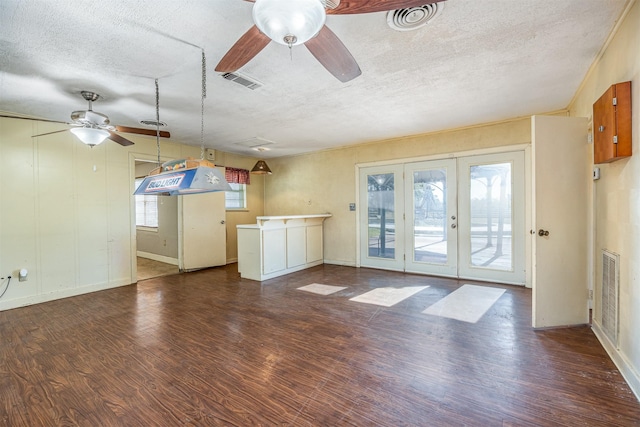 unfurnished living room featuring french doors, a textured ceiling, ceiling fan, and dark wood-type flooring