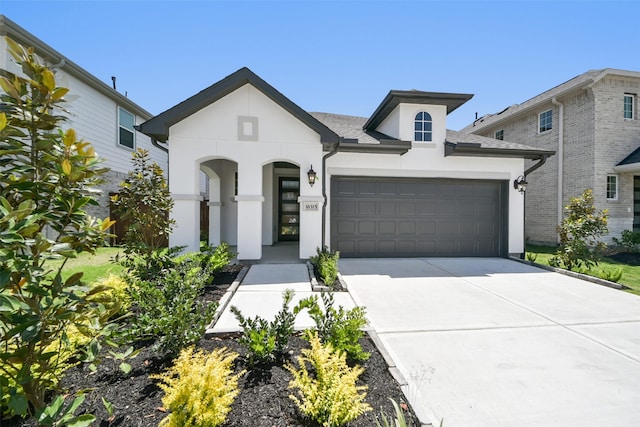 view of front facade with stucco siding, an attached garage, and driveway