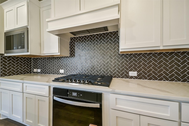 kitchen with stainless steel appliances, premium range hood, light countertops, decorative backsplash, and white cabinets