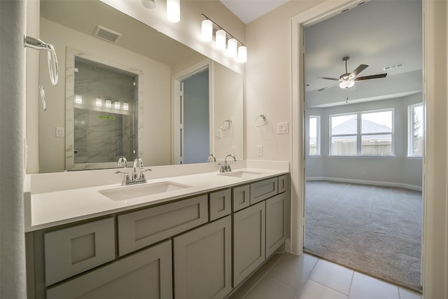 full bathroom with a marble finish shower, ceiling fan, baseboards, double vanity, and tile patterned flooring