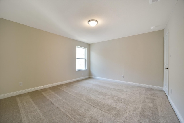 unfurnished room with baseboards and light colored carpet