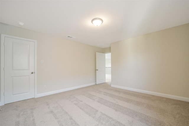 unfurnished room featuring light carpet and baseboards