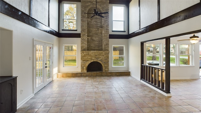 unfurnished living room with french doors, a fireplace, tile patterned flooring, and a ceiling fan