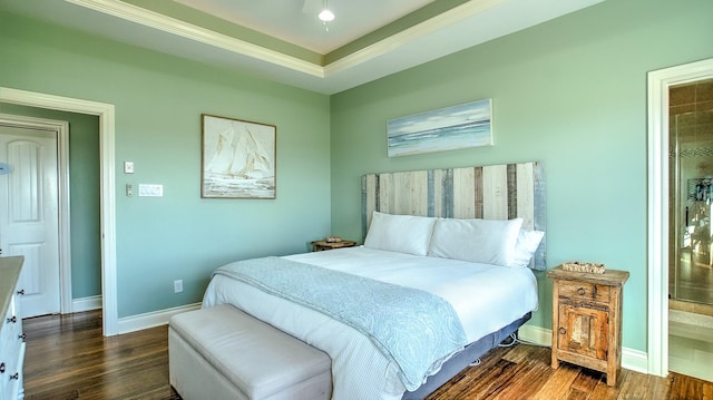 bedroom featuring dark hardwood / wood-style flooring, connected bathroom, and a tray ceiling