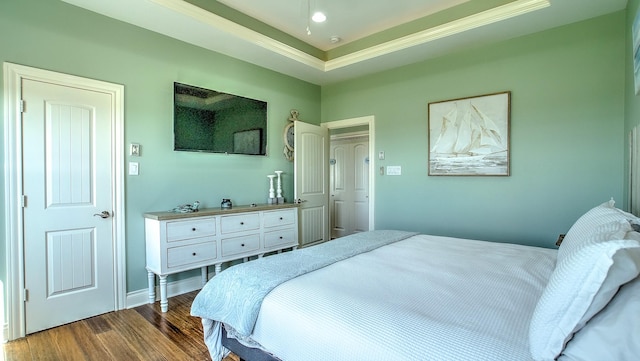 bedroom featuring dark hardwood / wood-style flooring, a raised ceiling, and crown molding