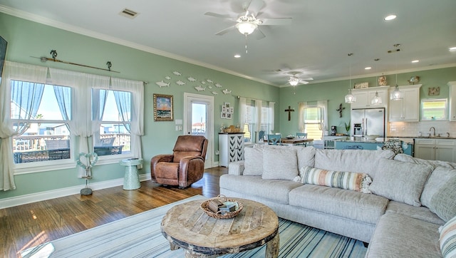 living room featuring a wealth of natural light, ornamental molding, and hardwood / wood-style flooring