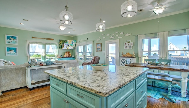 kitchen featuring pendant lighting, a center island, light wood-type flooring, and crown molding