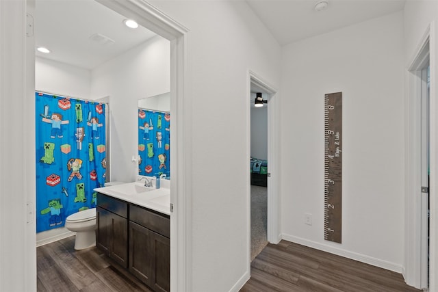 bathroom with toilet, hardwood / wood-style flooring, ceiling fan, a shower with shower curtain, and vanity