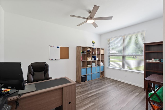 office with light wood-type flooring and ceiling fan