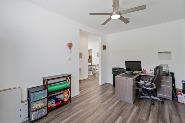 office with light wood-type flooring and ceiling fan