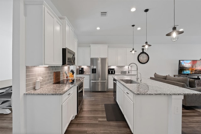 kitchen with sink, white cabinets, hanging light fixtures, a kitchen island with sink, and appliances with stainless steel finishes