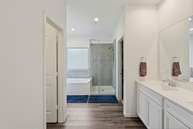 bathroom featuring vanity, hardwood / wood-style flooring, and plus walk in shower