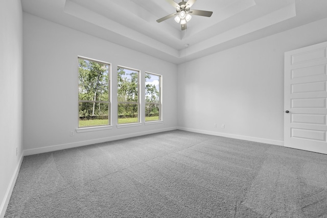 carpeted empty room featuring a raised ceiling and ceiling fan