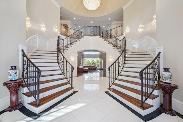 staircase featuring tile patterned floors, crown molding, and a towering ceiling