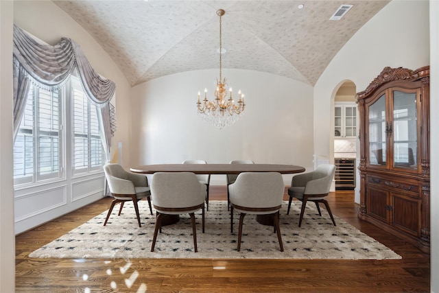 dining room with hardwood / wood-style flooring, brick ceiling, lofted ceiling, and an inviting chandelier