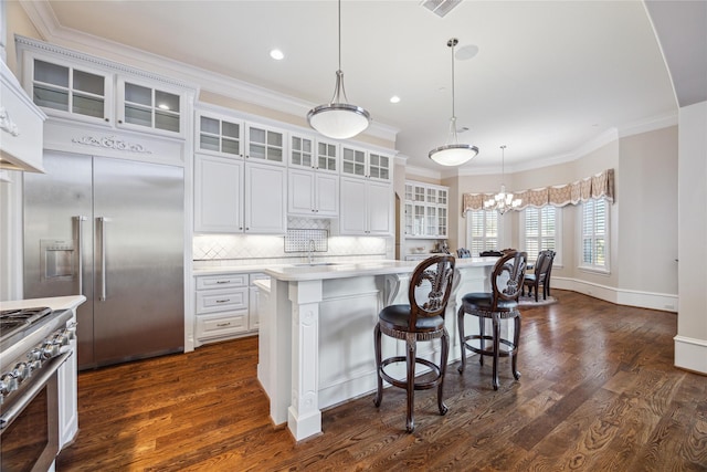 kitchen with high quality appliances, white cabinets, hanging light fixtures, and a center island