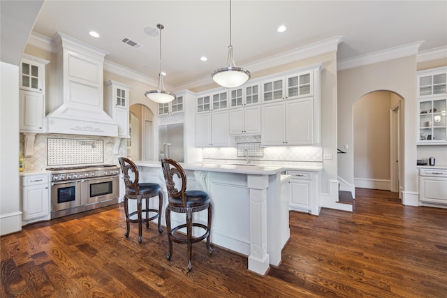 kitchen with premium range hood, white cabinets, decorative backsplash, and range with two ovens