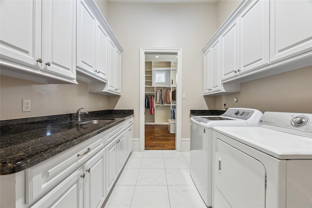 laundry room with light tile patterned floors, sink, separate washer and dryer, and cabinets