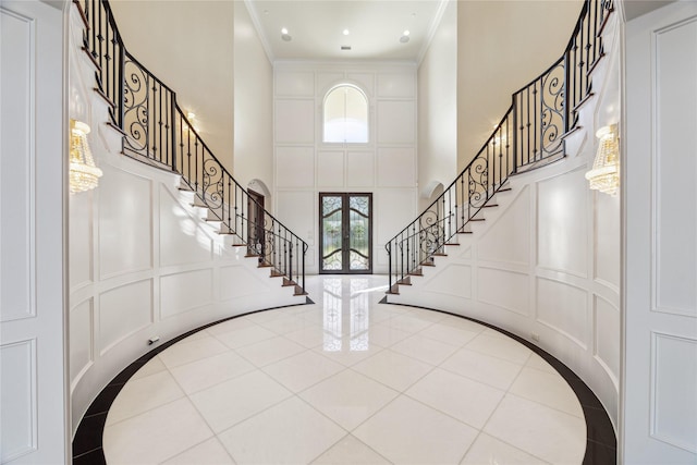 foyer entrance with a high ceiling, ornamental molding, and french doors