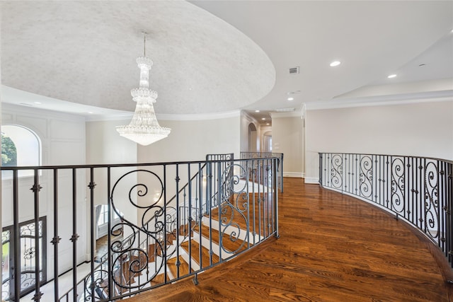 hallway featuring an inviting chandelier, dark hardwood / wood-style flooring, and crown molding