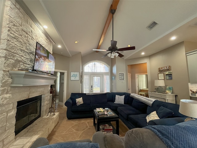 living room featuring lofted ceiling with beams, ceiling fan, and a stone fireplace