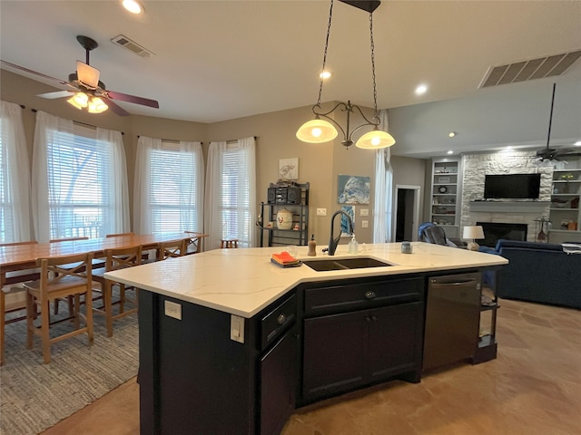 kitchen featuring dishwasher, a center island with sink, sink, built in features, and a fireplace