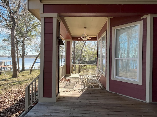 wooden deck with ceiling fan and a water view