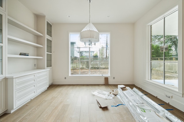 unfurnished dining area with light hardwood / wood-style floors and built in shelves