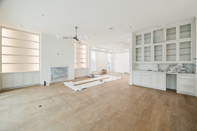 unfurnished living room featuring sink and an inviting chandelier