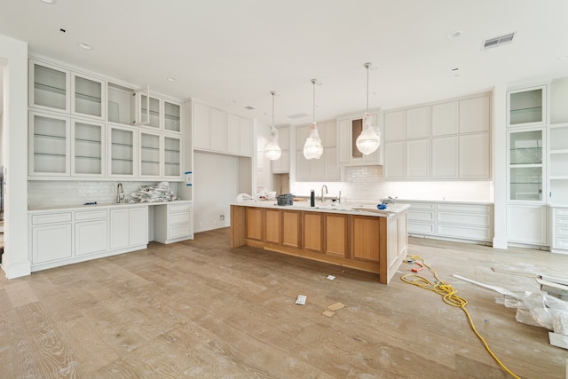 kitchen with decorative light fixtures, a large island, light wood-type flooring, and white cabinetry