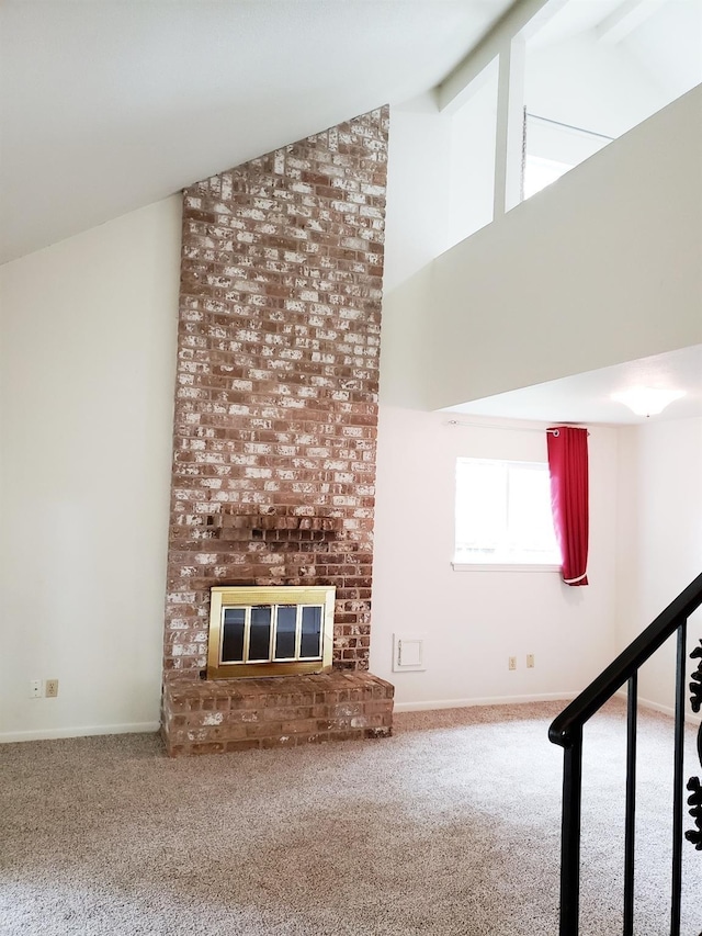 unfurnished living room with carpet flooring, lofted ceiling with beams, and a brick fireplace