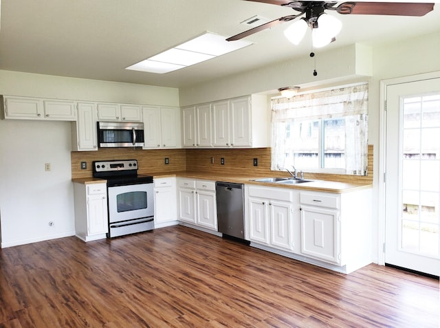 kitchen with tasteful backsplash, stainless steel appliances, dark wood-type flooring, sink, and white cabinetry
